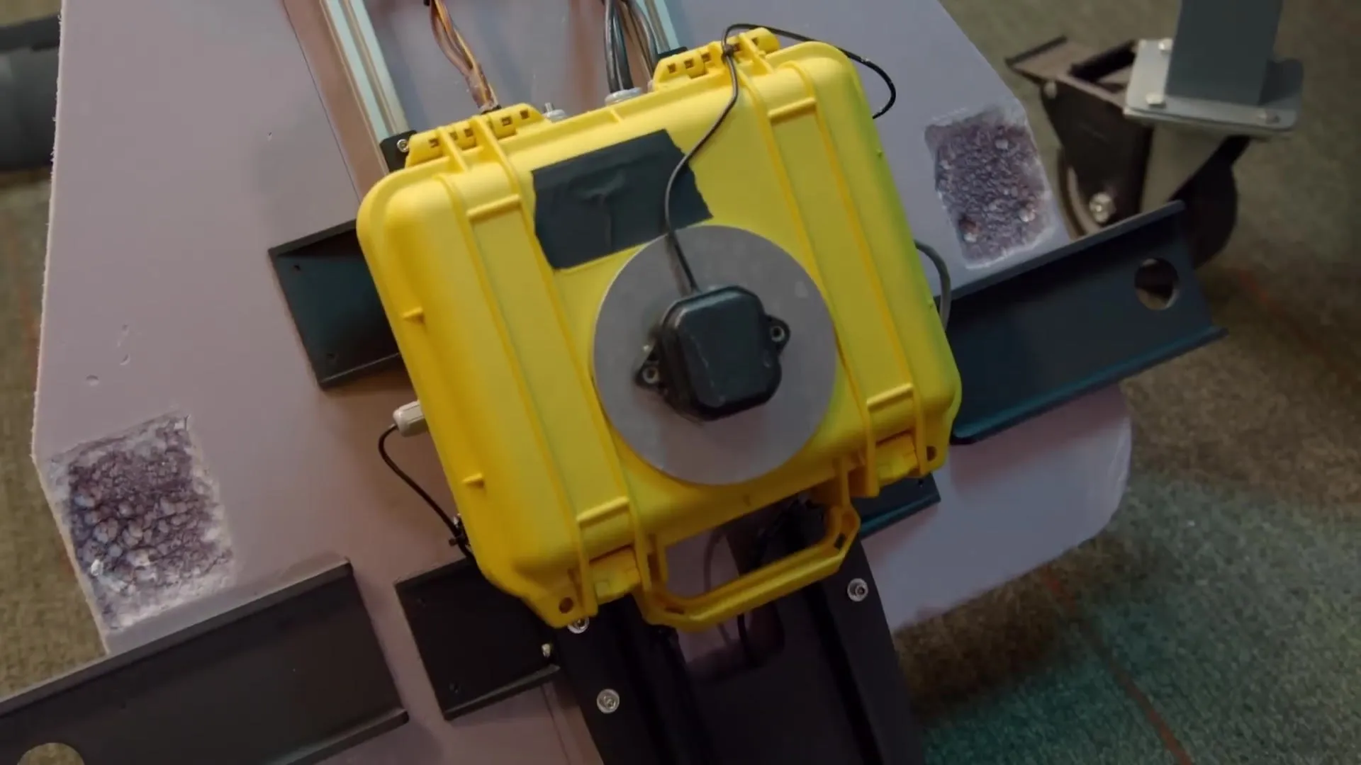 A yellow waterproof case with a GPS antenna on top, housing the navigation electronics.