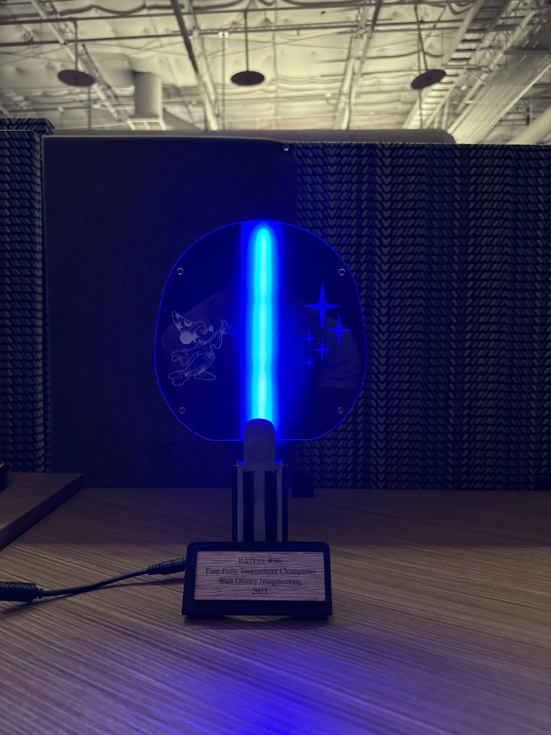 The finished trophy glowing blue in a dark room, its acrylic center lit from below by LEDs.