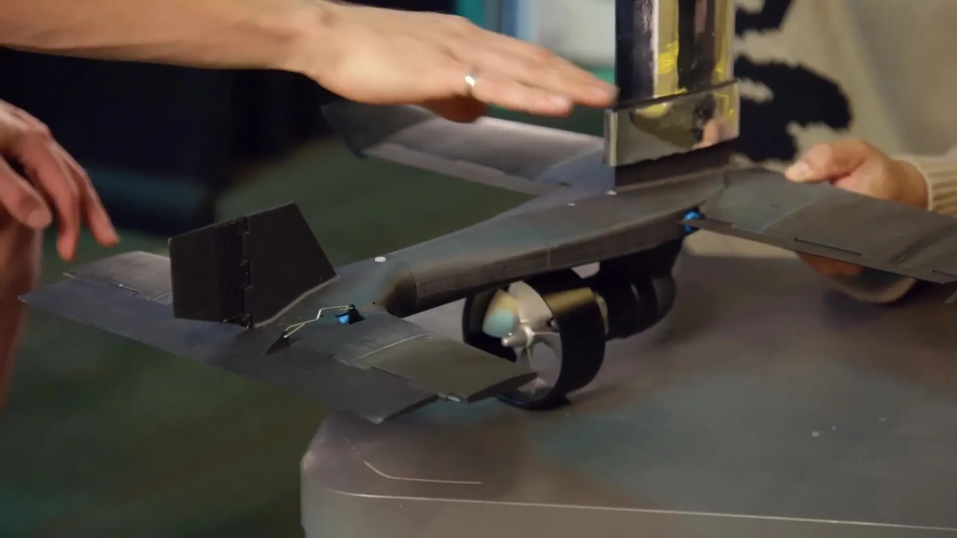 The black hydrofoil assembly on a workbench, with its wings, tail surfaces and a ducted thruster below the mast.