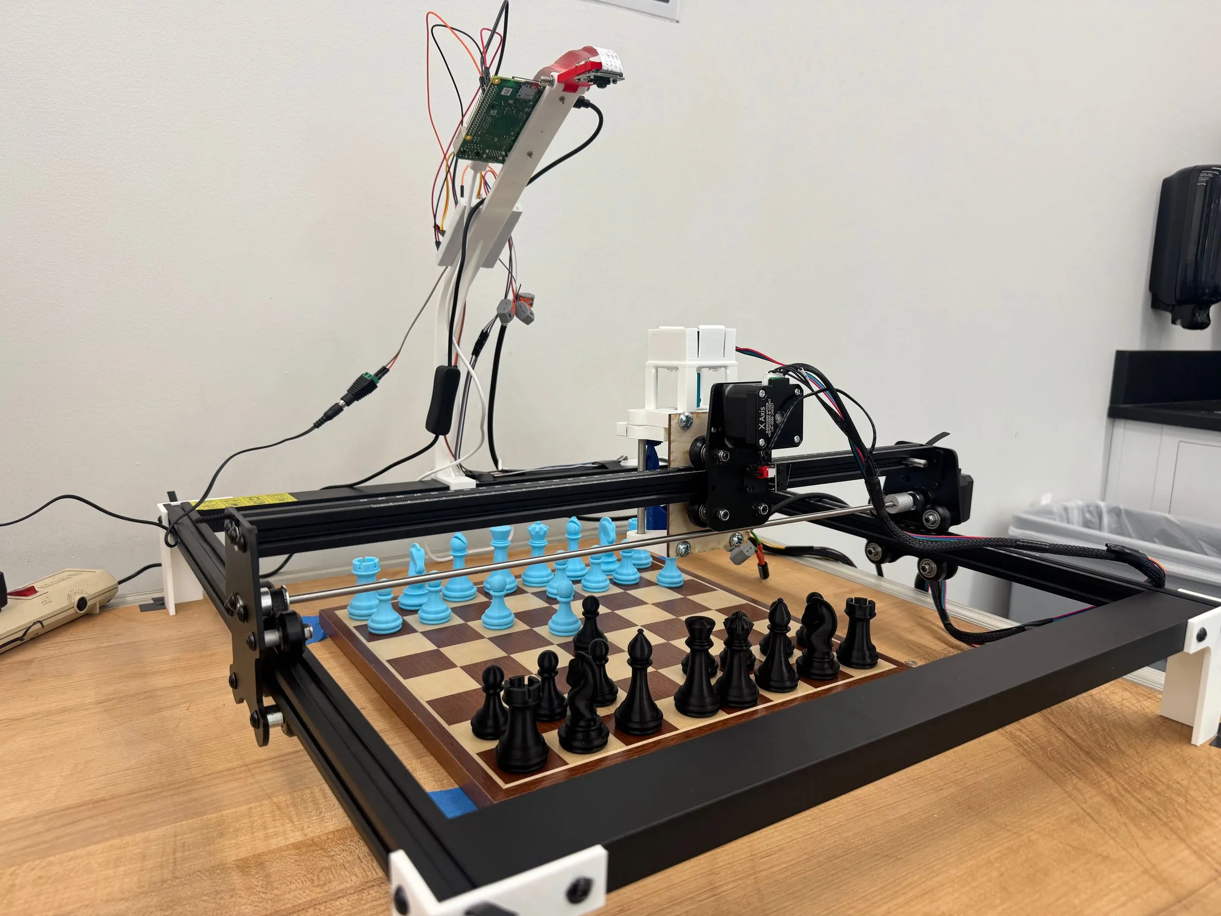 The full Sky Chess rig, an aluminum XY-gantry framed over a chessboard on a workbench.
