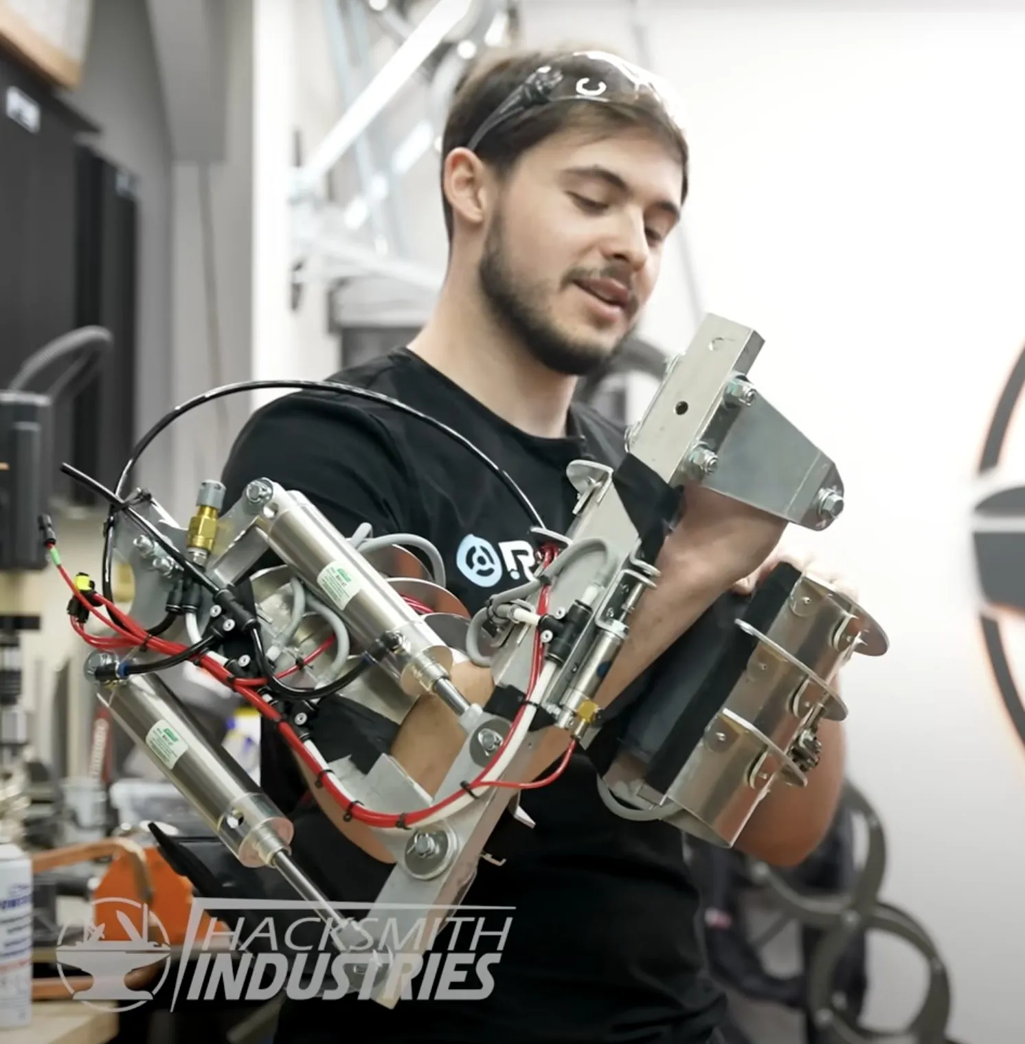 An engineer testing a power-arm prototype with exposed pneumatic cylinders and valves.
