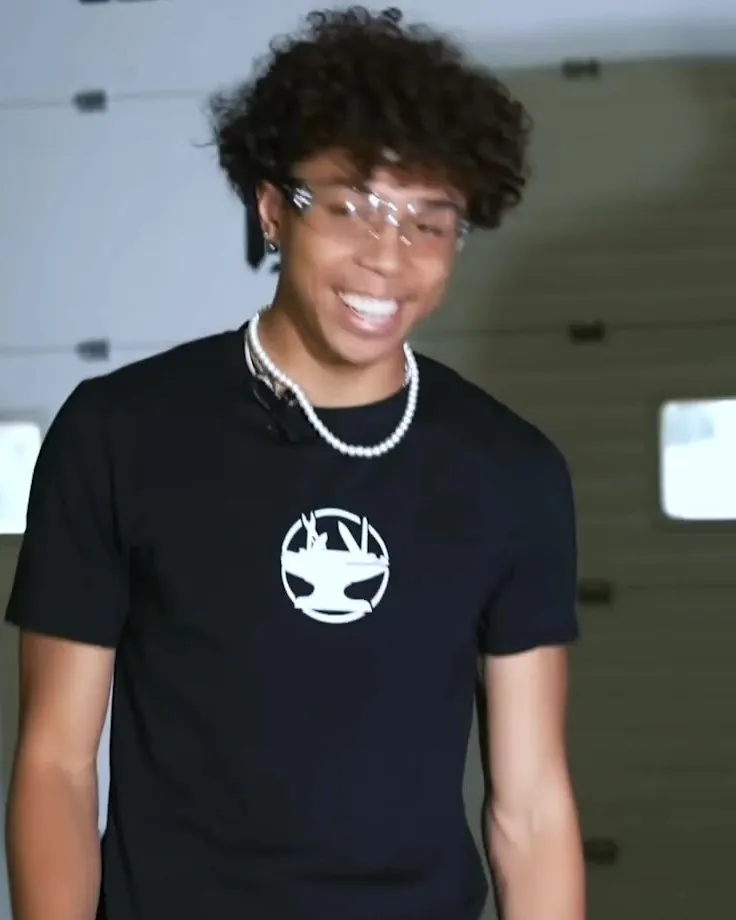 Nicolas Coleman smiling in the Hacksmith Industries shop, wearing safety glasses and a black Hacksmith T-shirt.