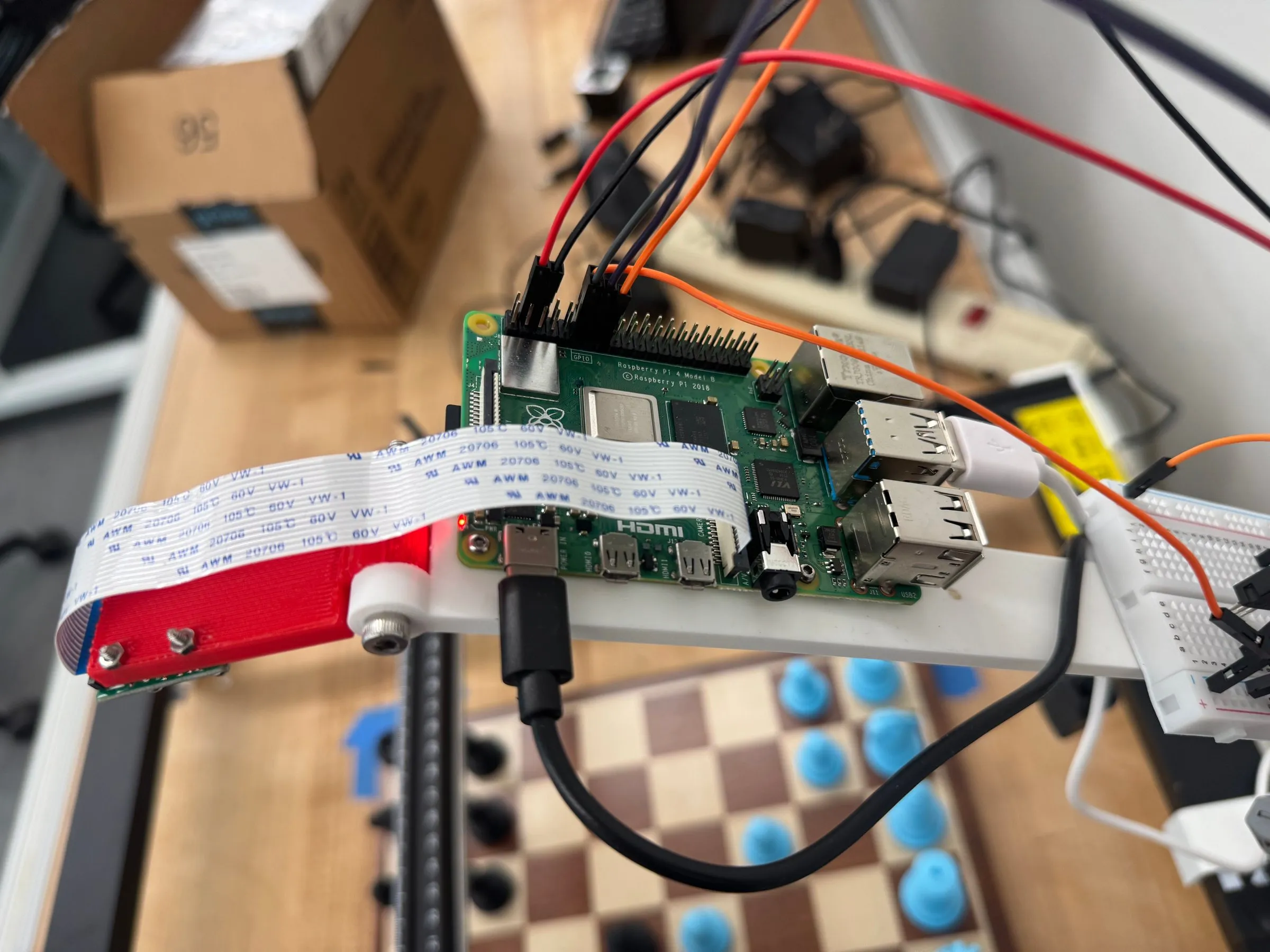 A Raspberry Pi and camera ribbon cable mounted on the gantry frame above the board.
