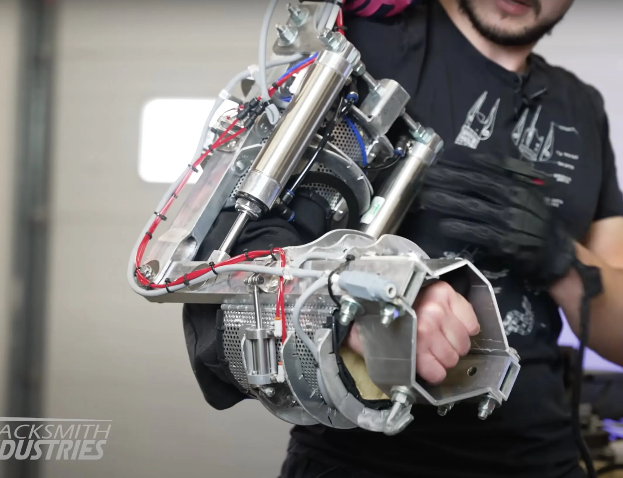 Close-up of a power arm showing the bent sheet-aluminum frame, pneumatic cylinders and wiring.